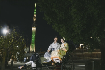 夜のイルミネーションが綺麗なスカイツリーと和装を着て人力車に乗った2人