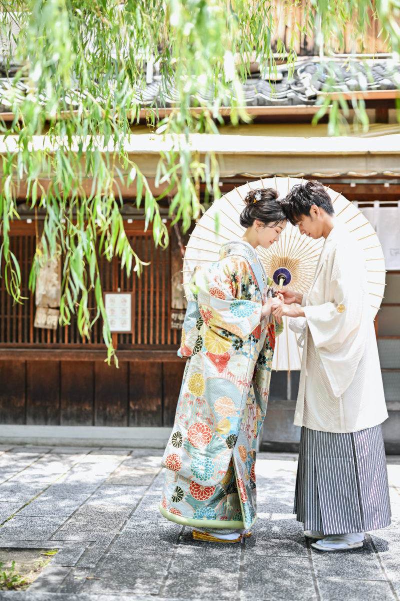 柳の木の下で向かい合っている和装姿の夫婦