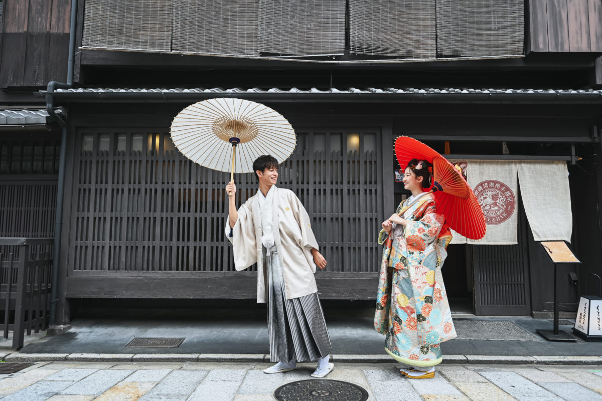 祇園の町を和傘を差して歩く夫婦。和装・洋装が選べる前撮り撮影より
