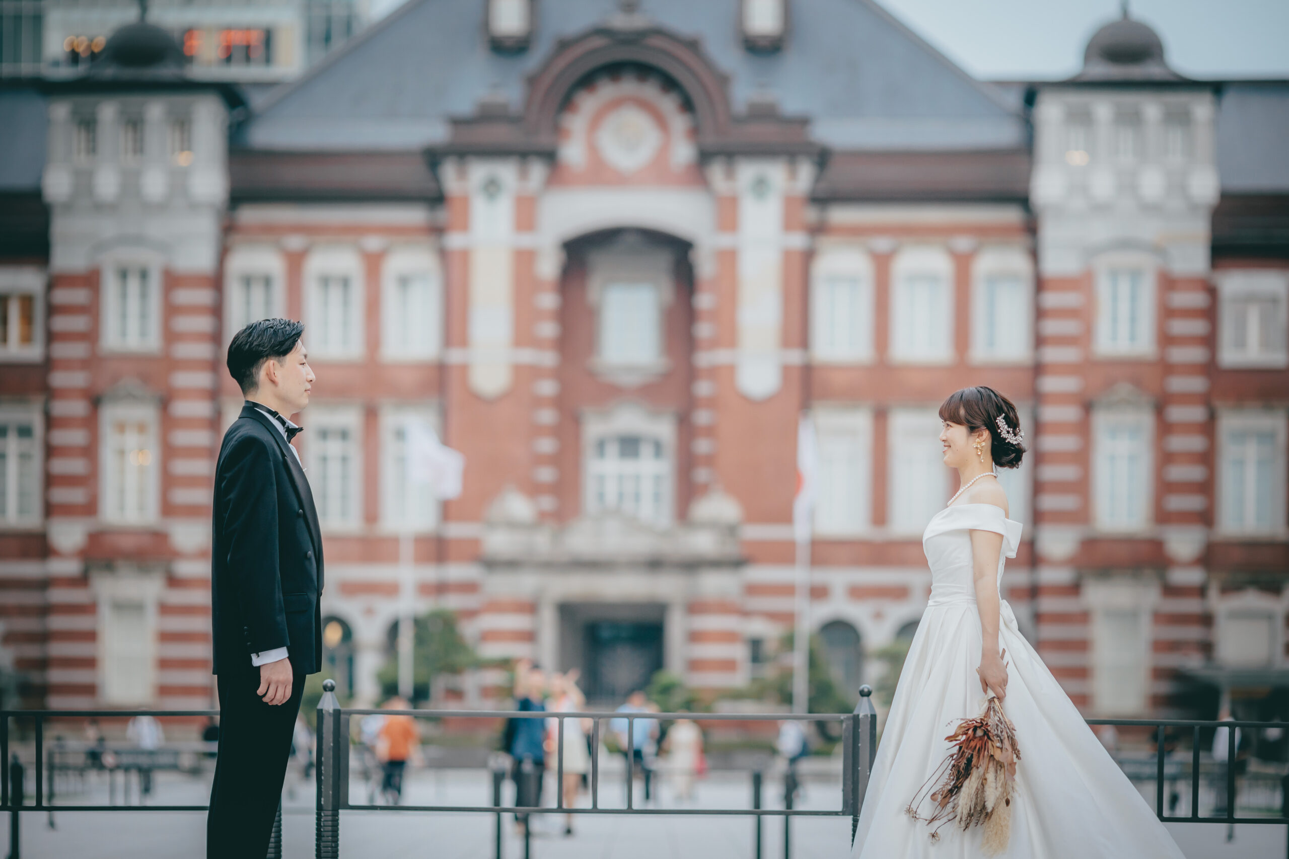 東京駅をバックにドレスとタキシードを着たふたりが向き合っている写真