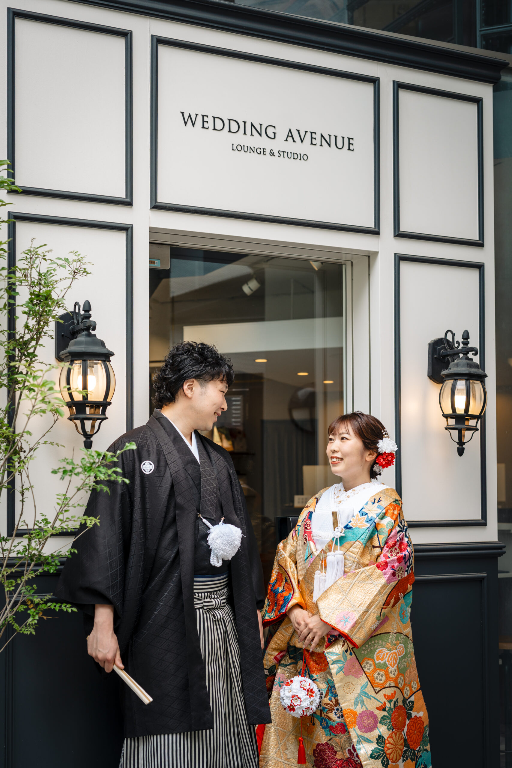 「WEDDING AVENUE」店舗前の新郎新婦 金地に極彩色の花柄が華やかな色打掛姿