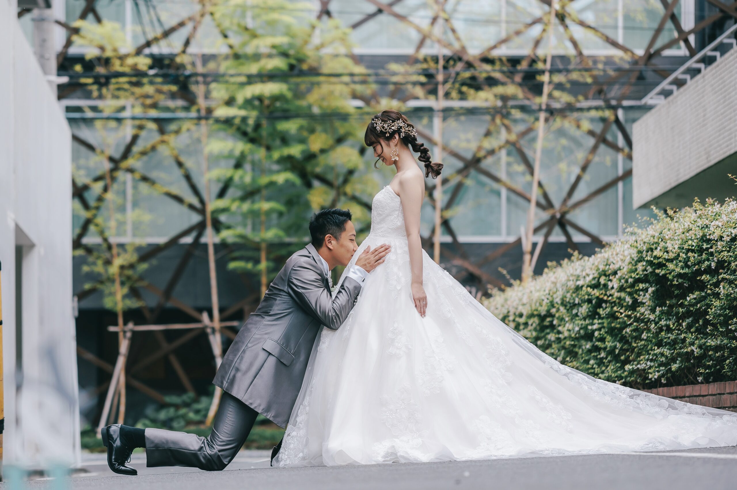 片膝をついて新婦への愛情を表現する新郎 総レース刺繍のストラップレスドレス姿