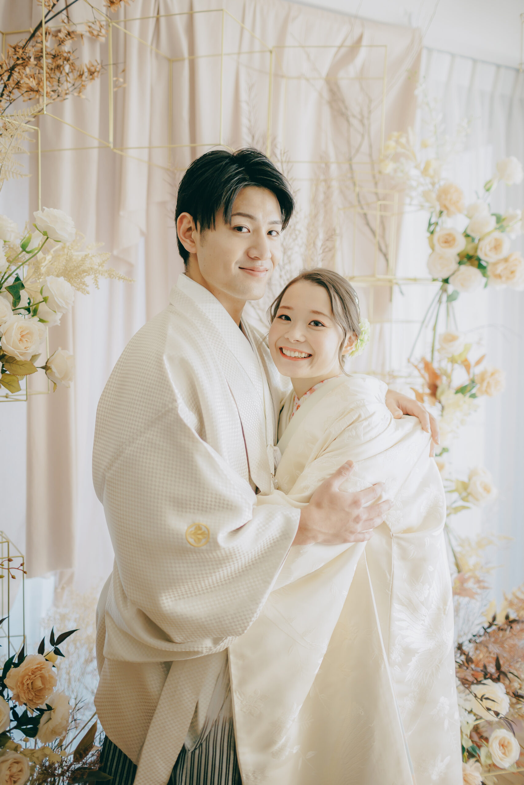 白無垢姿の新婦を優しく抱き寄せる新郎 ドライフラワーアーチを背景にした和装ショット