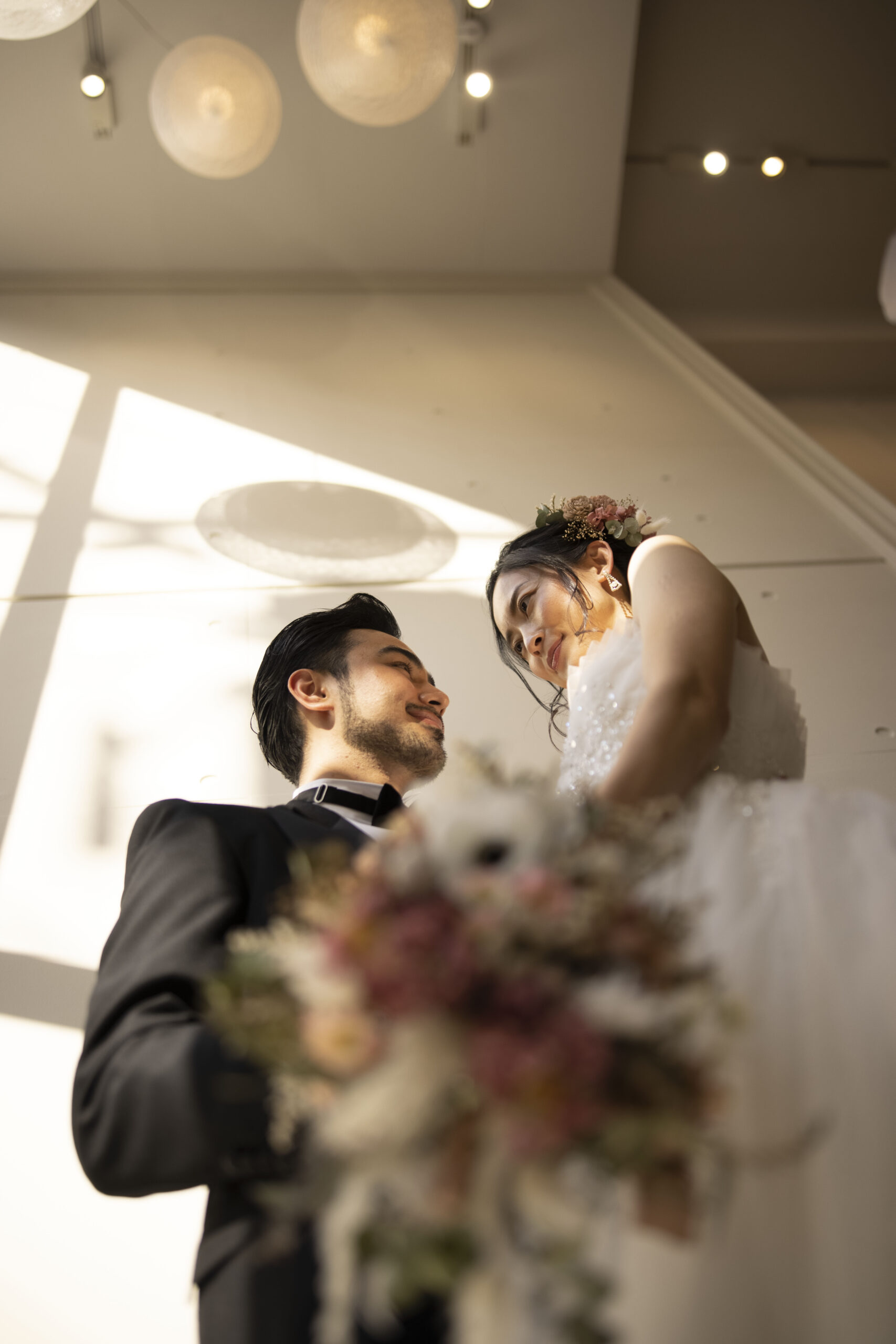 見上げるアングルで撮影された新郎新婦 きらめくビジューが施されたドレスとドライフラワーブーケ