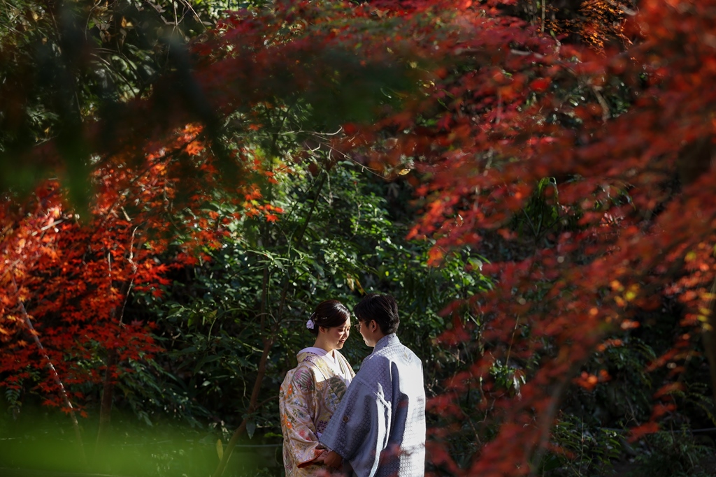 有栖川宮記念公園の紅葉シーズンでの和装前撮り実例、アーチ型の石橋と赤・黄の紅葉を背景に和装の色彩が豊かに輝く秋の一枚
