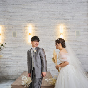 ファーストミートで花嫁の姿にまだ気付かない新郎と、そっと近づくウェディングドレスの花嫁をとらえたチャペルフォト