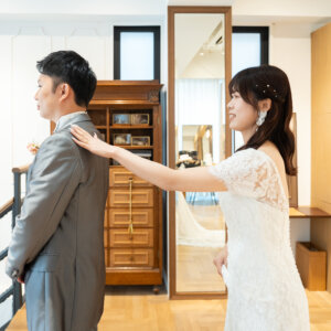 新郎の肩にそっと手を置いて呼びかける花嫁。ファーストミートの瞬間を写したスタジオでのウェディングフォト