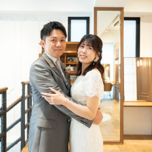 アンティークの棚と大きな鏡のある部屋で、抱き寄せ合ってカメラに笑顔を向ける新郎新婦。南青山店のスタジオで撮る前撮り