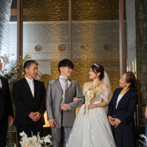 チャペルの祭壇前で家族と並んで笑顔を交わす新郎新婦。家族写真も一緒に残せるフォトウェディング