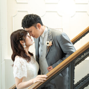 白い壁とアイアンの手すりの階段で、額を寄せ合って目を閉じる新郎新婦。ナチュラルな洋装前撮りの一枚