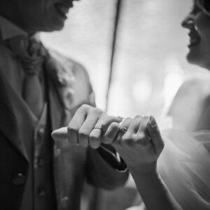 小指を絡めて約束を交わす新郎新婦の手元をとらえたモノクロの結婚写真。指輪がきらめくロマンチックなカット