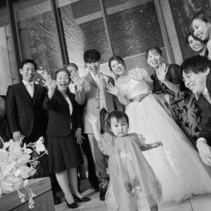 モノクロで撮った、チャペルに集まった家族や友人と手を振る新郎新婦の集合写真。ゲストと過ごす結婚写真の一コマ