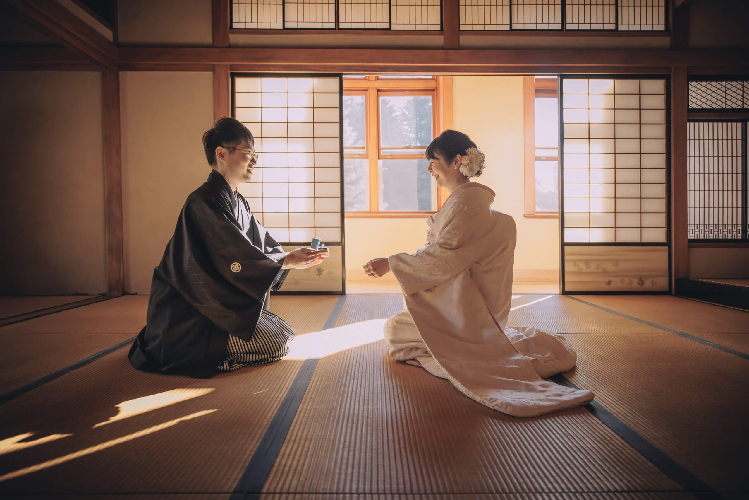 旧古河邸の和室で、畳の上に座って向き合う紋付袴の新郎と白無垢の新婦の和装前撮り