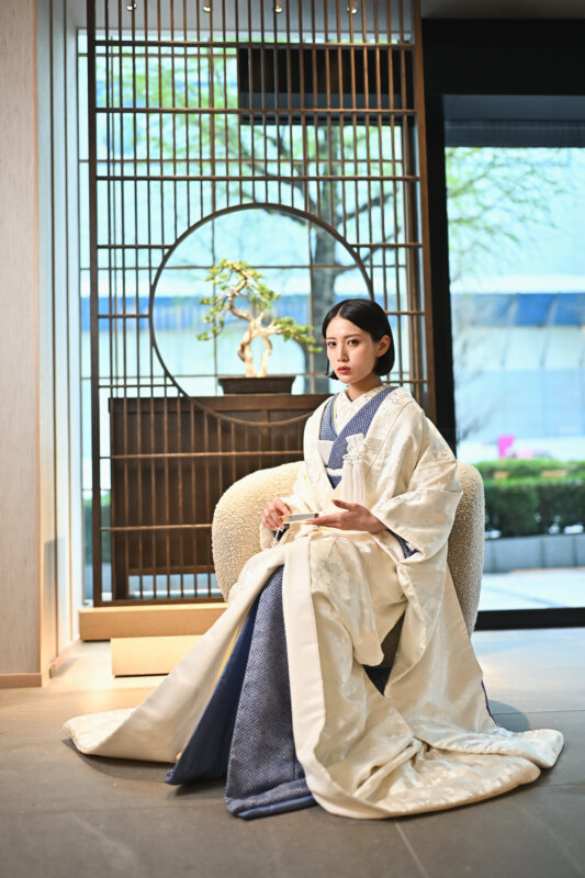 丸窓と盆栽のある和モダンな空間で椅子に座る白無垢の花嫁。白無垢AS103を着た和装前撮りの座りポーズ
