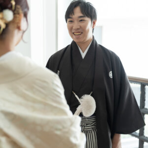 花嫁の肩越しに写す、笑顔で迎える黒紋付袴の新郎。南青山のスタジオで撮る和装前撮りの、ファーストミートの表情を切り取った一枚