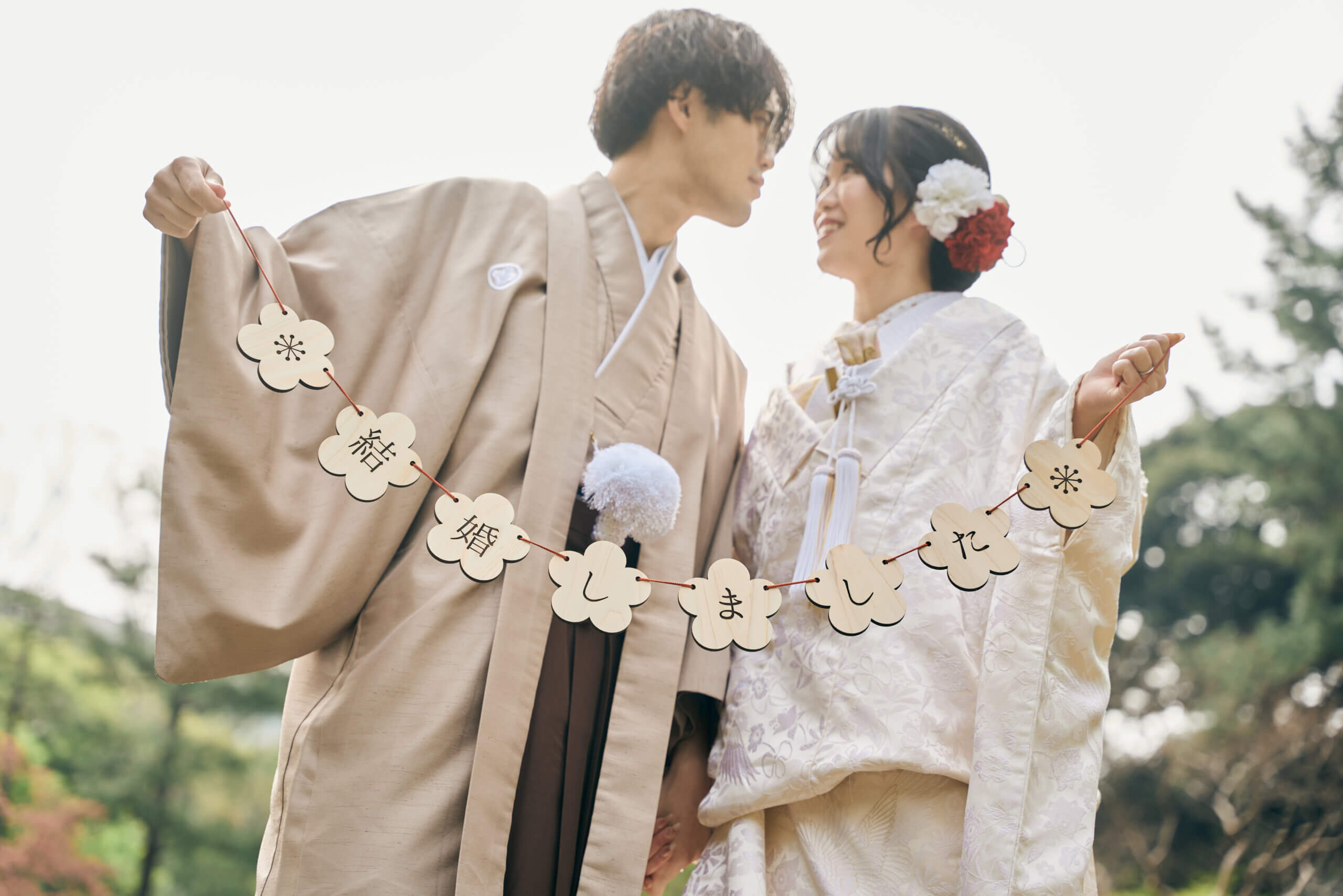 甘泉園公園の池と木々を背景に佇む和装の新郎新婦の引きの写真