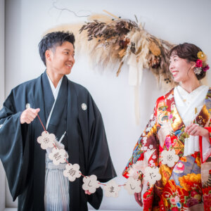 '結婚しました'のガーランドを持って見つめ合う紋付袴の新郎と赤い色打掛の花嫁。南青山のスタジオで撮る和装前撮り
