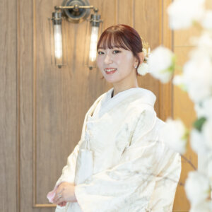 木目の扉とランプの前で、振り返ってほほえむ白地の色打掛の花嫁。スタジオで撮る和装前撮りの、花嫁の上品なソロカット