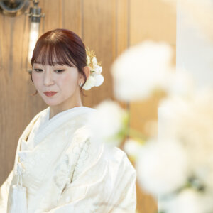 白い花越しに伏し目がちに写す、髪飾りをつけた色打掛の花嫁。南青山のスタジオフォトで撮るしっとりとした和装前撮り