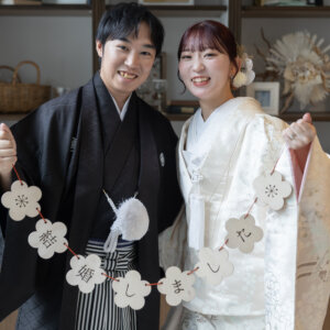 '結婚しました'のガーランドを二人で掲げる紋付袴の新郎と色打掛の花嫁。結婚報告にも使えるスタジオでの和装前撮り